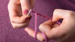 deux mains avec des aiguilles à tricoter qui exécutent une maille